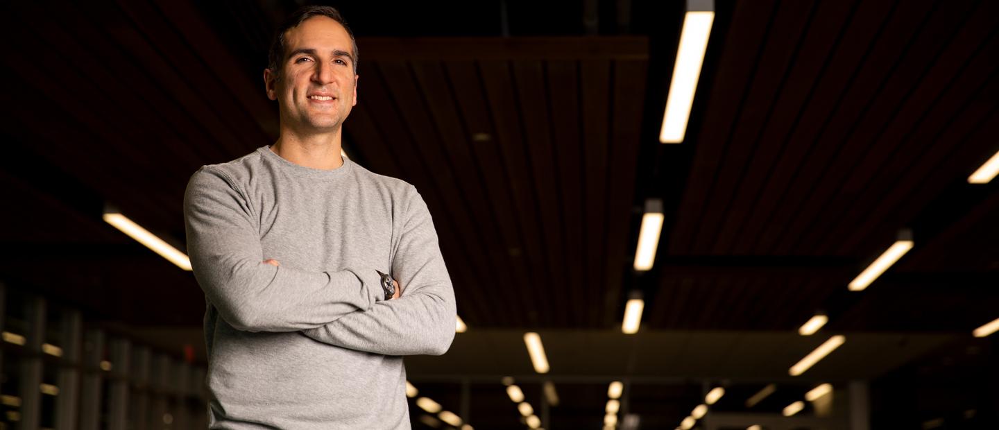 Image of a smiling man standing with his arms crossed